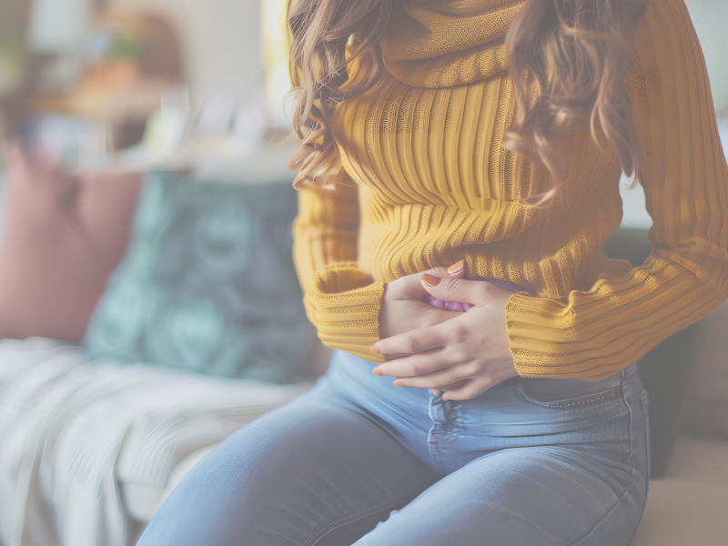 Frau mit Wärmflasche auf dem Bauch und der Gebärmutter